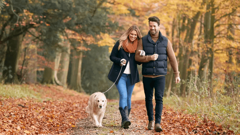 Young-Couple-Walking-A-Dog-In-The-Park-During-The-Fall-Season.png